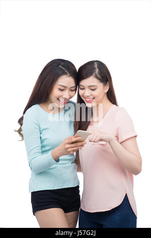 Two young girls using smart phone. Smiling young female friends reading text message Stock Photo