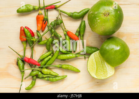 Small chilli and lemon on wood chopping block. Stock Photo