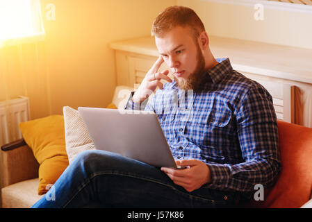 Young man working absorbed on laptop at home. Stock Photo