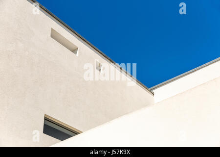 Striking Architectural Corner detail of modern white rendered building with clear blue sky Stock Photo