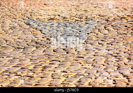 Granite dichromatic cobblestone pavement detail with triangle shape and limited DOF in warm morning light Stock Photo