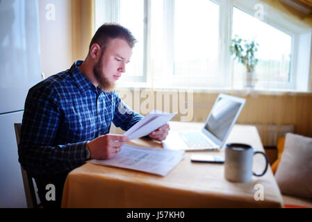 Handsome man doing some paperwork at home. Stock Photo