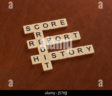 Crossword puzzle with words Credit, History, Report, Score. Credit concept. Ivory tiles with capital letters on mahogany board. Stock Photo