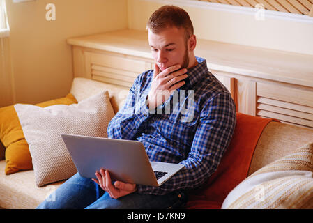 Young man working absorbed on laptop at home. Stock Photo