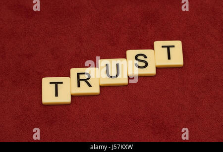 Trust sign. Loyalty concept. Ivory tiles with capital letters on red velure. Stock Photo