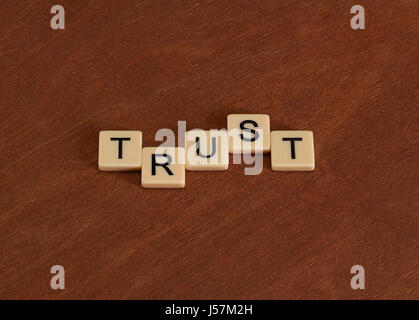 Trust sign. Loyalty concept. Ivory tiles with capital letters on mahogany board. Stock Photo