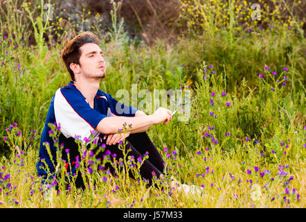 lonely man smokes a cigarette in a field Stock Photo