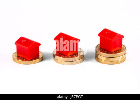 Red Houses sitting on top of stacks of coins, over a white background. Stock Photo