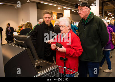 People getting help and support from a staff member in using the self service checkout  in the Food Hall  in the Marks and Spencer store, Aberystwyth Wales UK Stock Photo