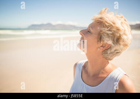 Close up of smiling senior woman with eyes closed standing at beach Stock Photo