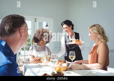 Waitress serving food to customers in restaurant Stock Photo