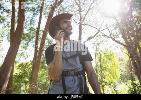 Smiling man talking on the mobile phone in forest on a sunny day Stock Photo