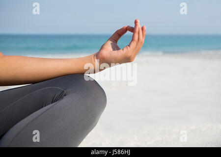 Cropped image of woman meditating at beach on sunny day Stock Photo