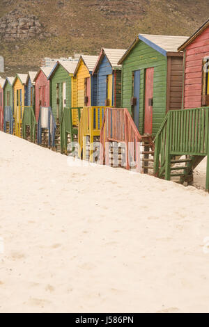 Multi colored wooden huts on sand against mountain at beach Stock Photo