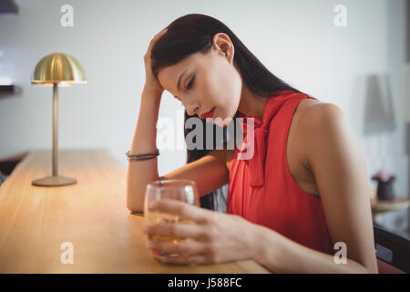 Thoughtful woman having a glass of whisky in restaurant Stock Photo