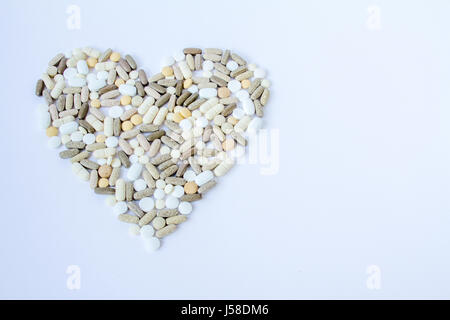 Colorful medical pills loose in the form of heart on a white background. Stock Photo