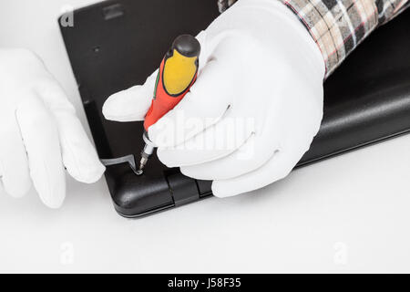 serviceman in white gloves disassembles laptop with screwdriver and tweezers Stock Photo