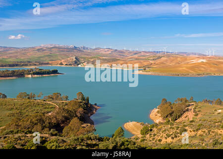 View across Guadalhorce dam, Malaga Province, Andalusia, Spain, to farmland and wind turbines beyond. Embalse de Conde de Guadalorce. Stock Photo