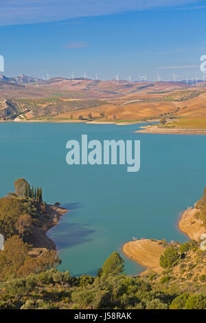 View across Guadalhorce dam, Malaga Province, Andalusia, Spain, to farmland and wind turbines beyond. Embalse de Conde de Guadalorce. Stock Photo