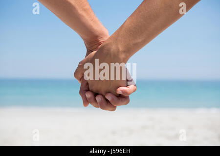 Cropped hands of couple holding hands at beach Stock Photo