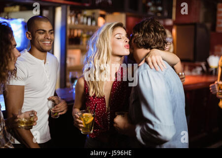 Friends looking at woman embracing man while standing in club Stock Photo