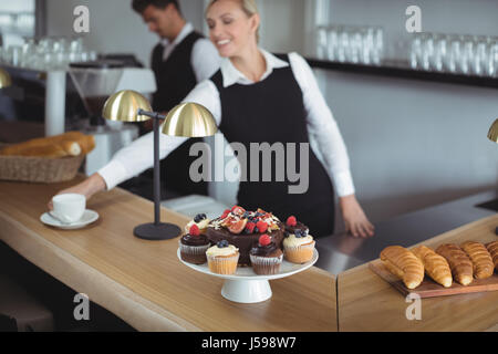 Waitress serving coffee at counter in restaurant Stock Photo