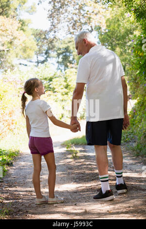 Grandfather and granddaughter holding hands while walking in the forest Stock Photo