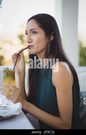 Woman having cocktail while relaxing on sofa at restaurant Stock Photo