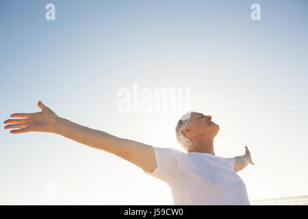 Active senior man with arms outstretched standing against clear sky Stock Photo