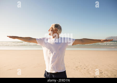 Senior man practicing yoga at beach Stock Photo
