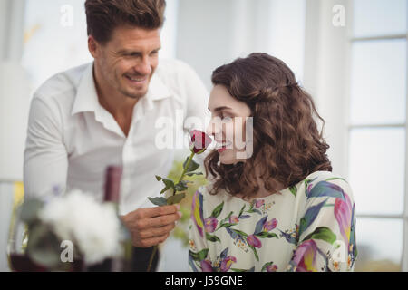 Beautiful woman smelling rose in restaurant Stock Photo