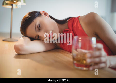 Portrait of tensed woman having a glass of whisky in restaurant Stock Photo
