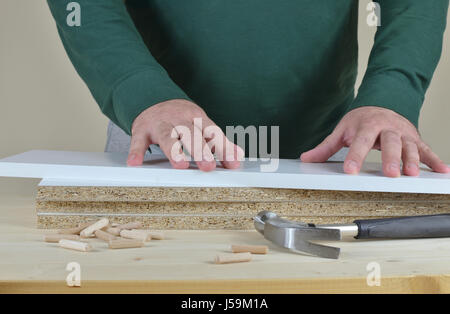 Man's hands on a pile of particle boards set on working table Stock Photo