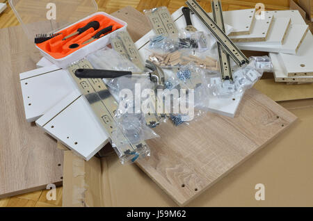 Pile of just unpacked elements of a new chest of drawers ready for assembling and tools Stock Photo