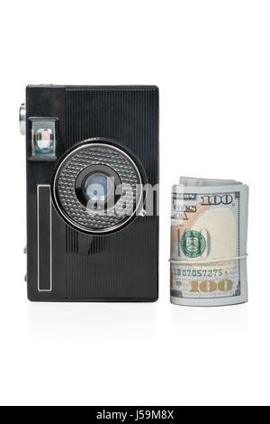 Old retro camera in vertical position and a bundle of money rolled up in a tube isolated on a white background Stock Photo
