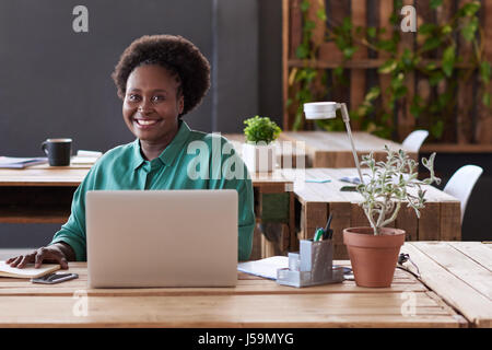 Smiling African businesswoman working at an office desk  Stock Photo