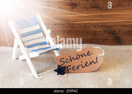 Sunny Summer Label With Sand And Aged Wooden Background. German Text Schoene Ferien Means Happy Holidays. Deck Chair For Holiday Or Vacation Feeling. Stock Photo