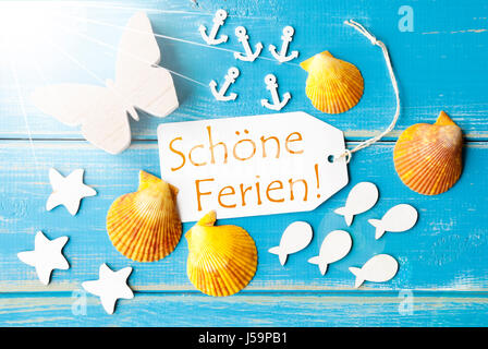 Flat Lay View Of Label With German Text Schoene Ferien Means Happy Holidays. Sunny Summer Greeting Card. Butterfly, Shells And Fishes On Blue Wooden B Stock Photo
