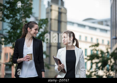 Portrait of two caucasian business women talking outside modern office buidling. Stock Photo