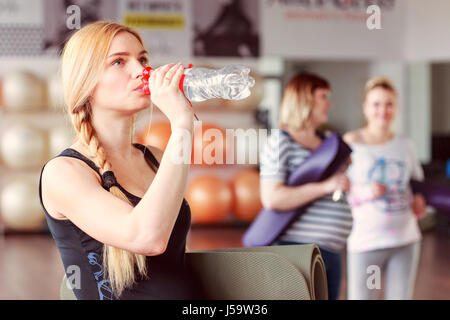 Young blond haired woman drinking water after fitnes training Stock Photo