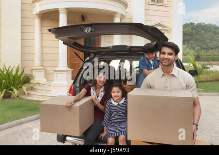 Family unpacking cardboard boxes from car Stock Photo