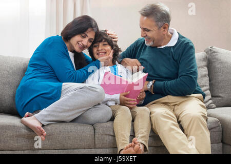 Grandson reading book to grandparents Stock Photo