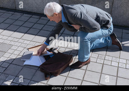 Awkward pensioner dropping bag from his hand outdoors Stock Photo