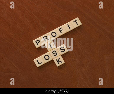 Crossword puzzle with words Risk, Profit and Loss. Risk management concept. Ivory tiles with capital letters on mahogany board. Stock Photo