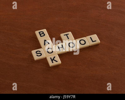 Crossword puzzle with words Back To School. Education concept. Ivory tiles with capital letters on mahogany board. Stock Photo