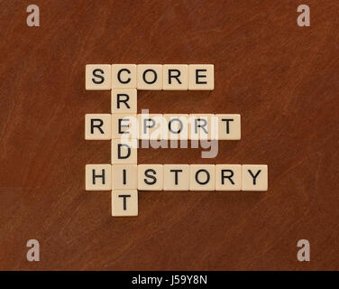 Crossword puzzle with words Credit, History, Report, Score. Credit concept. Ivory tiles with capital letters on mahogany board. Stock Photo