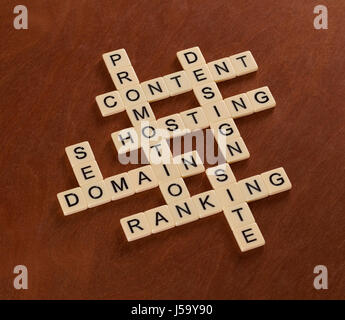 Crossword puzzle with words SEO, Content, Site, Ranking. Web Site Creation concept. Ivory tiles with capital letters on mahogany board. Stock Photo