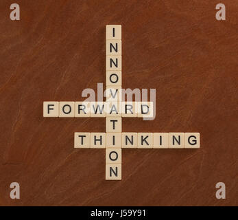 Crossword puzzle with words Innovation, Forward, Thinking. Innovate concept. Ivory tiles with capital letters on mahogany board. Stock Photo