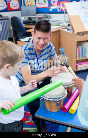 Nursery teacher playing with musical instruments with his student. Stock Photo
