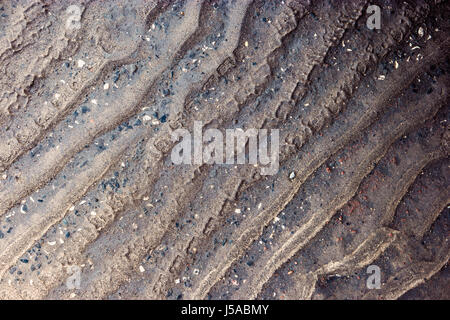 Waves of sand on asphalt road after rain from above Stock Photo